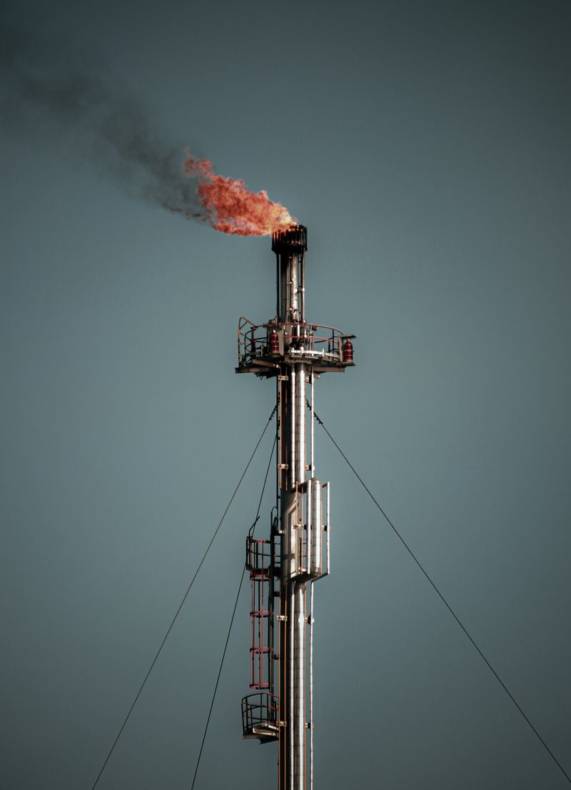 Oil and gas production facility with flare stacks at dusk